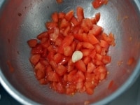 トマトは湯煎にかけ皮むきをし、種を丁寧に取り除いて、1cm角のダイスカットにする。にんにくをこすりつけたボウルに入れ、塩、オリーブオイルをかけて5分程置いておく。<br />