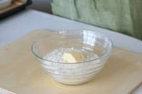 粉の入ったボウルに、冷やしておいたバターを入れる。<br />