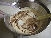 3のボウルに、湯煎して溶かしたチョコレートバターと生クリームを加え、混ぜ合わせます。<br />