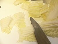 白菜は白い部分を削ぎ切りにし、葉の部分をザクザク切る。豚肉は大きければ2～3cm角に切る。<br />