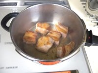 豚バラ肉は5cm角くらいに切ります。圧力鍋にサラダ油小さじ1を入れ中火にかけます。ばら肉の前面をこんがりと焼きます。次に肉がかぶくらいの水を加え、生姜も入れて蓋をして一度茹でます。<br />