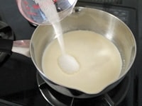 鍋に生クリーム、牛乳、グラニュー糖を合わせて、泡立て器でよくかき混ぜながら、グラニュー糖が完全に溶けるまで中火で加熱します。<br />