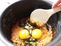 炊けたら生卵を割り入れて、さっくり混ぜてお茶碗によそう。半分をそのまま食べて、残り半分に卵を混ぜて食べるのもお勧め！<br />