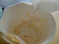 卵が馴染んだら、振っておいた粉とベーキングパウダーを加え混ぜ合わせ、そこに牛乳を加えて混ぜる。<br />
