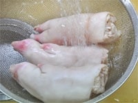 下処理された豚足はさっと水で洗います。生姜は汚れをとったら皮をむかず薄切りにします。長ねぎも薄切りにします。<br />