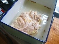 鶏がぴったりと収まるサイズの容器に、茹で上がった鶏を皮目を下にして入れ、鶏の煮汁2カップとコリアンダー、塩を加え、そのまま粗熱を取ります。 <br />