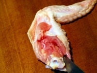 続いて大きい骨の周囲にナイフを入れ、骨と肉を繋ぐ筋を切ります。 <br />