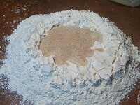 中心のくぼんだ部分にイーストを流しいれ、周囲の粉を少しずつ、手で混ぜていきます。