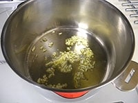 鍋にオリーブオイルとニンニクを入れ、中火弱で炒めます。<br />