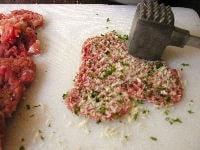 豚肉の表面に丸く塩コショウをしたら、パン粉をまぶして豚肉に軽くたたきこむようにします。2～3回この作業を繰り返し、パン粉をしっかりと豚肉の表面につけます。