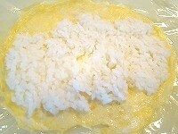 ラップに2で作った薄焼き卵を敷き、その上にご飯を薄く平らに置きます。（特に細巻サイズに薄焼き卵を切らず、そのまま使います）