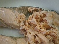 茹でた鮭を皿などにあげてほぐし、骨と皮を丁寧に取り除きます。<br />