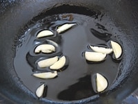 フライパンにオリーブオイルとニンニクを入れ弱火で熱し、オイルに香りをつけます。ニンニクの香りが漂ってきたら、取り除きます。<br />