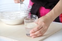 水にインスタントドライイーストをふり入れ、1～2分おいてから、よく混ぜ溶かす。<br />
