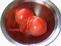 冷凍トマトは水につけ、皮を剥きます。<br />