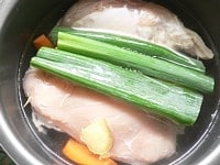 内釜に鶏肉、ショウガ、青ねぎを入れ、水と酒を注ぎ入れる