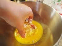 卵を割って、しろみときみをしっかりあわせる。小麦粉をつけたトマトに、卵をつける<br />