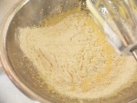 ふるっておいた小麦粉をふるいながら加え、ミキサーの低速で混ぜる。ダマがなくなるまでよく混ぜ合わせる。 <br />