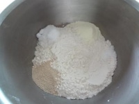 ボウルに強力粉、イースト、砂糖、塩、スキムミルクを入れざっくりと混ぜます。この時、塩とイーストは隣接しないように気をつけましょう。<br />
<br />
