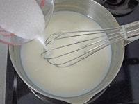 鍋に牛乳を入れ、グラニュー糖を加えます。中火で加熱しながら、グラニュー糖が完全に溶けるまで、泡立て器でよく混ぜます。<br />