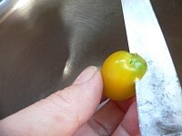味を沁み込みやすくするために、ミニトマトのヘタの部分を少し削り取る。<br />