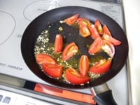 にんにくの香りが立ってきたら、トマトを加え炒めます。<br />