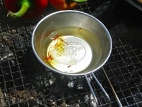 焼き網に５０ｃｃ程度の水を入れたシェラカップを置き、少し温めます。ぬるま湯になったら火から外し、サフラン一つまみを加えてそのまま置き、サフランの色と香りを抽出させたサフラン水を作ります。