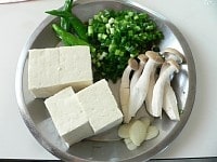 豆腐は4つに切る。しめじは小分けする。青唐辛子はヘタを取る。ねぎは小口切り、ニンニクは薄切りにする。<br />