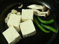 フライパンにサラダ油とニンニクを入れて火にかけ、熱くなったところで豆腐、しめじ、青唐辛子を入れて焼く。<br />
<br />