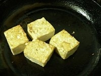ニンニクをカリッと焼いて取り出す。椎茸と唐辛子は火が通ったら盛りつけ用の鉄板に移す。豆腐は全面をゆっくりじっくり焼いて中まで火を通す。<br />