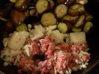 フライパンの手前でニンニク、赤唐辛子、たまねぎ、挽き肉を炒める。<br />
