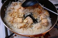 たまねぎがしんなりしたら、ぶつ切りにし、塩（分量外）とこしょうをした鶏胸肉を加える。 鶏肉に焼き色がついたら米を加えてよく混ぜ、米に油がまんべんなく絡むようにする。
