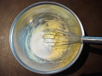 室温に戻したバターを、空気を含んでふわっとしたクリーム状になるまで、泡立て器でよく混ぜます。バターが白っぽくなったら、グラニュー糖を加え、ざらざらした感じがなくなるまで、さらに良く混ぜます。<br />