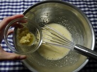 ときほぐした卵にグラニュー糖を加え、グラニュー糖のザラザラが無くなるまで、泡立て器でよく混ぜます。蜂蜜、皮ごとすりおろした生姜を加え、さらに良く混ぜます。<br />