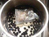 鍋に洗った黒豆、水、ティーバックを入れて中火にかける。<br />