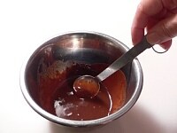 小さいボウルに砕いたチョコと牛乳を入れ、55℃ぐらいの湯にしばらく浮かべておく。やわらかくなったところで湯煎から外し、スプーンで混ぜて溶かしてチョコレートソースを作る。<br />
<br />