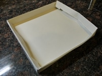 二重にしたわら半紙を使い、20cmX20cmの正方形にスポンジ用の型紙を作ります。写真のように、縁を二重にし、中に折り込むように作ると丈夫になります。卵は室温に戻します。薄力粉とカカオパウダーは合わせて2回ふるいます。<br />