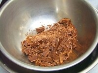 チョコを包丁で刻んでボウルに入れ、そのボウルをお風呂より熱い程度のお湯を入れた別のボウルの中に浮かべ、湯煎でチョコを溶かす。 