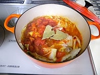 トマトの水煮缶、水、スープの素を加え混ぜ合わせます。ローリエをちぎって加えます。蓋をして沸騰したらアクを取り除き、弱火で40分ほど煮込みます。<br />