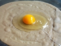 ガレットの生地をフライパンなどに広げ、中心に卵を割り入れる。<br />
<br />
<a href="../7723/">ガレット（そば粉のクレープ）の作り方はこちら</a>