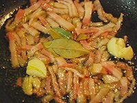 フライパンに、たたいてつぶしたニンニクと、細切りにしたベーコン、オリーブ油、ローリエを入れて弱火にかけます。ニンニクの香りが立ち、ベーコンが色づくまで炒めます。