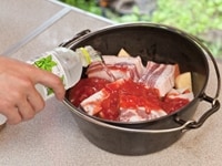 ダッチオーブンにタマネギ、ジャガイモ、ニンジンを敷いて、その上にスペアリブを載せる。トマトカット缶を投入し、食材がヒタヒタに浸かる程度水を入れる。