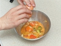 残り物の野菜を1、2cm角程度のサイズに細かく切り（潰しても可）、ボールに入れる。ここに生卵を二つ割って投入したら、具材と絡まるようにしっかりとかき混ぜる。この時、塩も適量入れる。<br />
