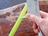茎の縁に包丁の刃で軽く切り込みを入れるようにして、筋をはがしとり、引きむきます。同様にして、全ての筋を取ります。