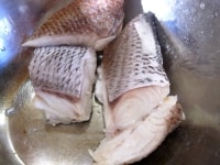 鯛の色が変わり、煮汁のなかに固まったアクが出てきたら（水の温度は60℃程度）、鯛を取り出す。