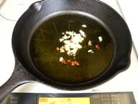 ニンニクはみじん切りにします。赤唐辛子は種を取りみじん切りにします。鍋にオリーブオイルとニンニク、赤唐辛子入れ、中火にかけます。<br />