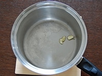 大きめの鍋にオリーブオイルとにんにくを入れたら弱火にかけて香りを引き出します。香りが漂ってきたら、にんにくを取り出します。<br />