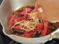 せん切りの生姜も、よく水気を切って牛肉と同じタイミングで加えます。火加減を中火に落として、牛肉に火を通します。