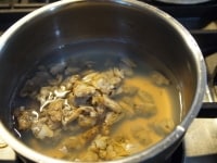 あさりの水煮缶を汁ごとと、水200ccを鍋に入れて火にかけます。沸騰したらあくをひきます。<br />
