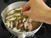 分量のだしを鍋に入れて火にかけ、沸いてきたらしいたけとモロヘイヤの茎を加えて火を通します。